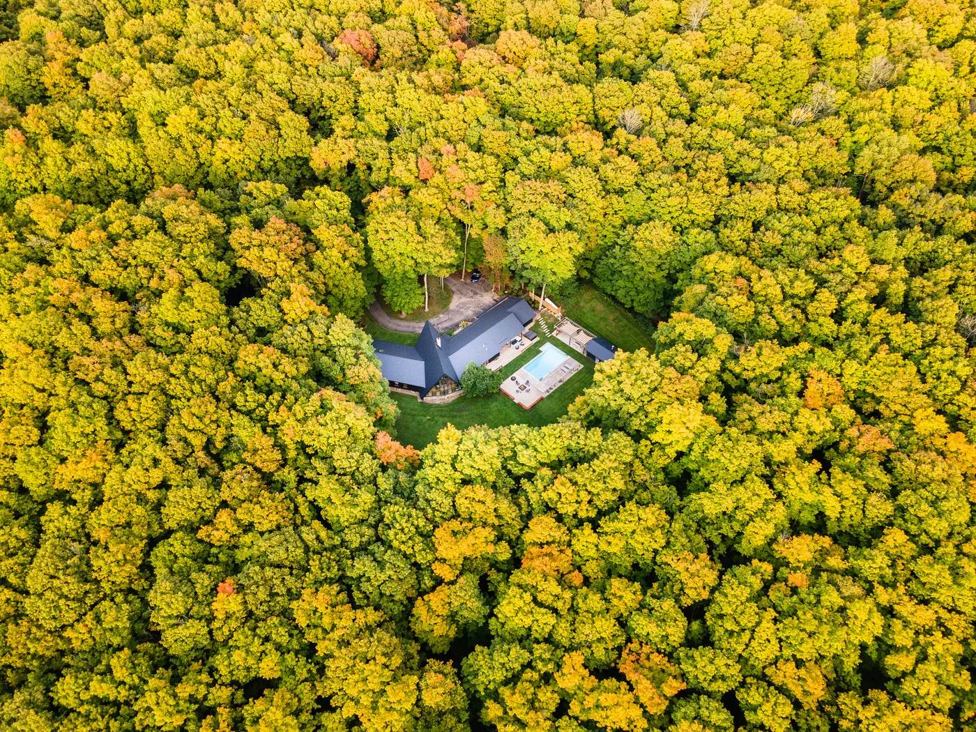 Aerial drone photograph of a property surrounded by autumn forest